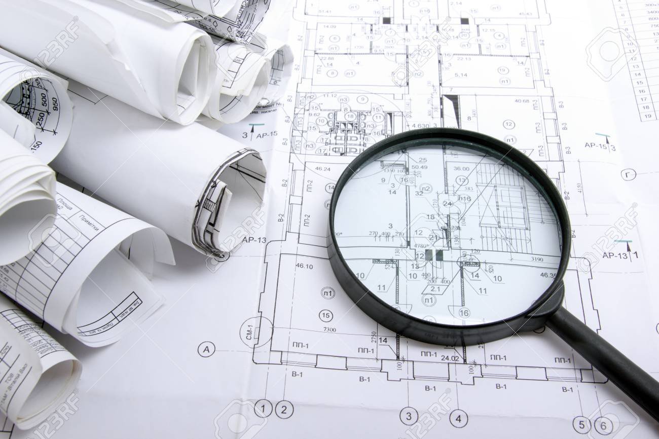 Architectural blueprints, blueprint rolls and magnifying glass on white background